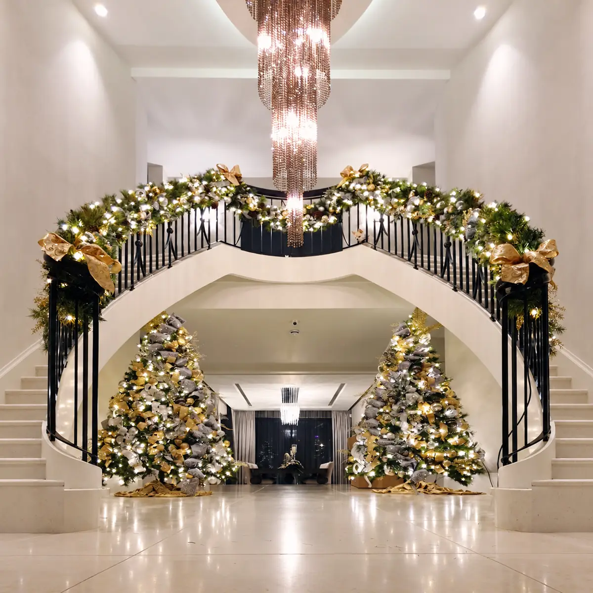 Entrance hall with a garlanded double staircase and two decorated Christmas trees