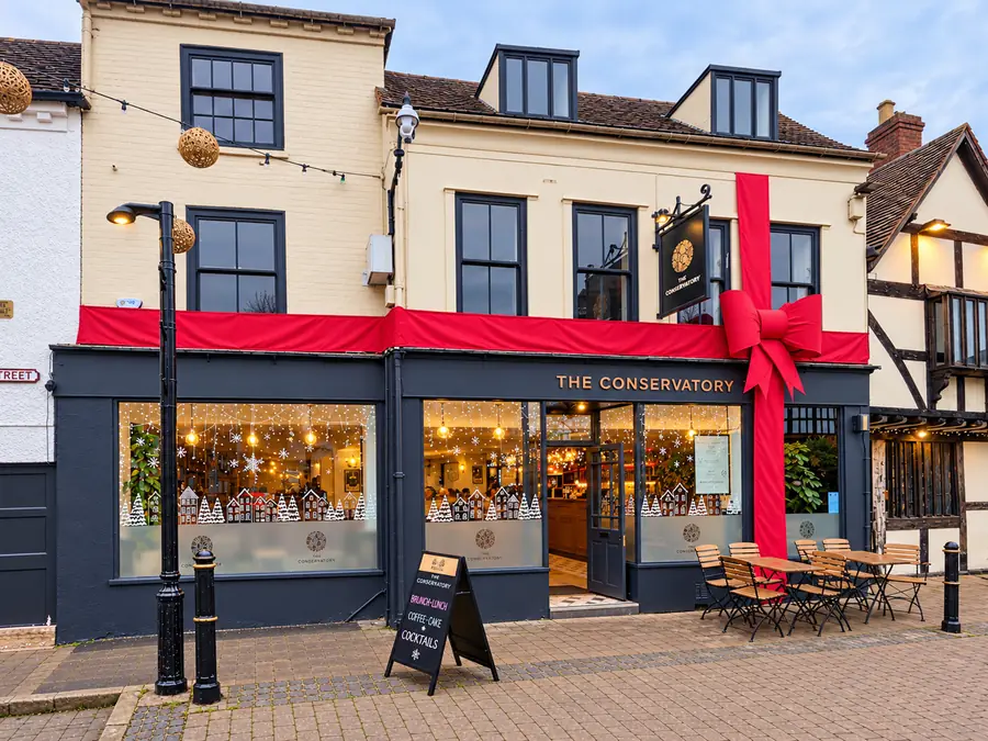 Shopfront in Worcester wrapped in a giant red ribbon and bow, with festive window displays