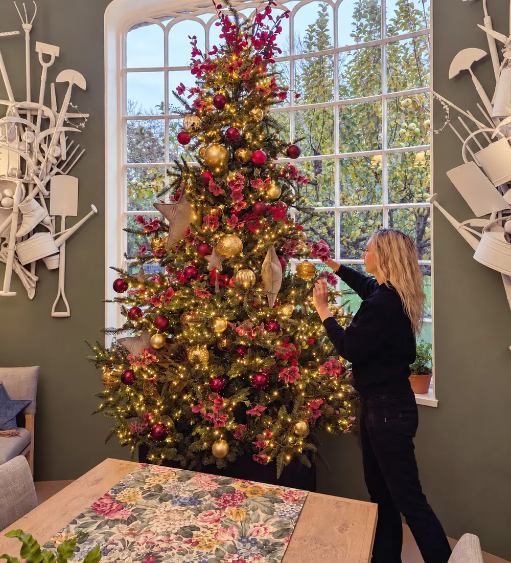 Lamorna adding the finishing touches to a red and gold Christmas tree